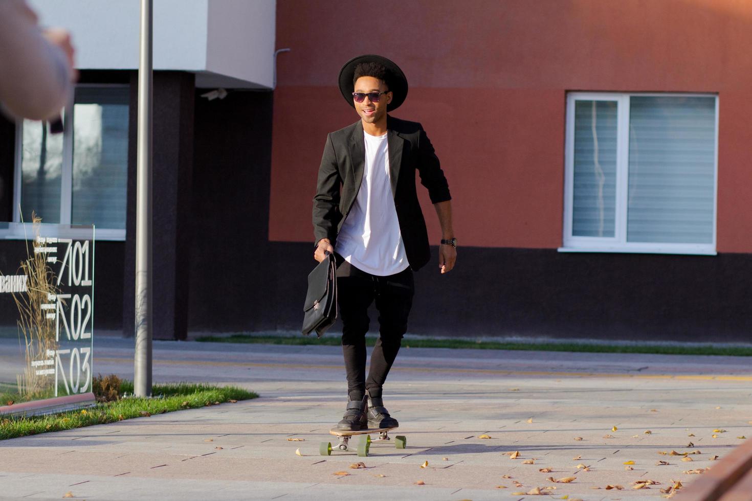 conceito de gerente jovem, rápido e móvel. empresário engraçado no skate em terno preto. foto