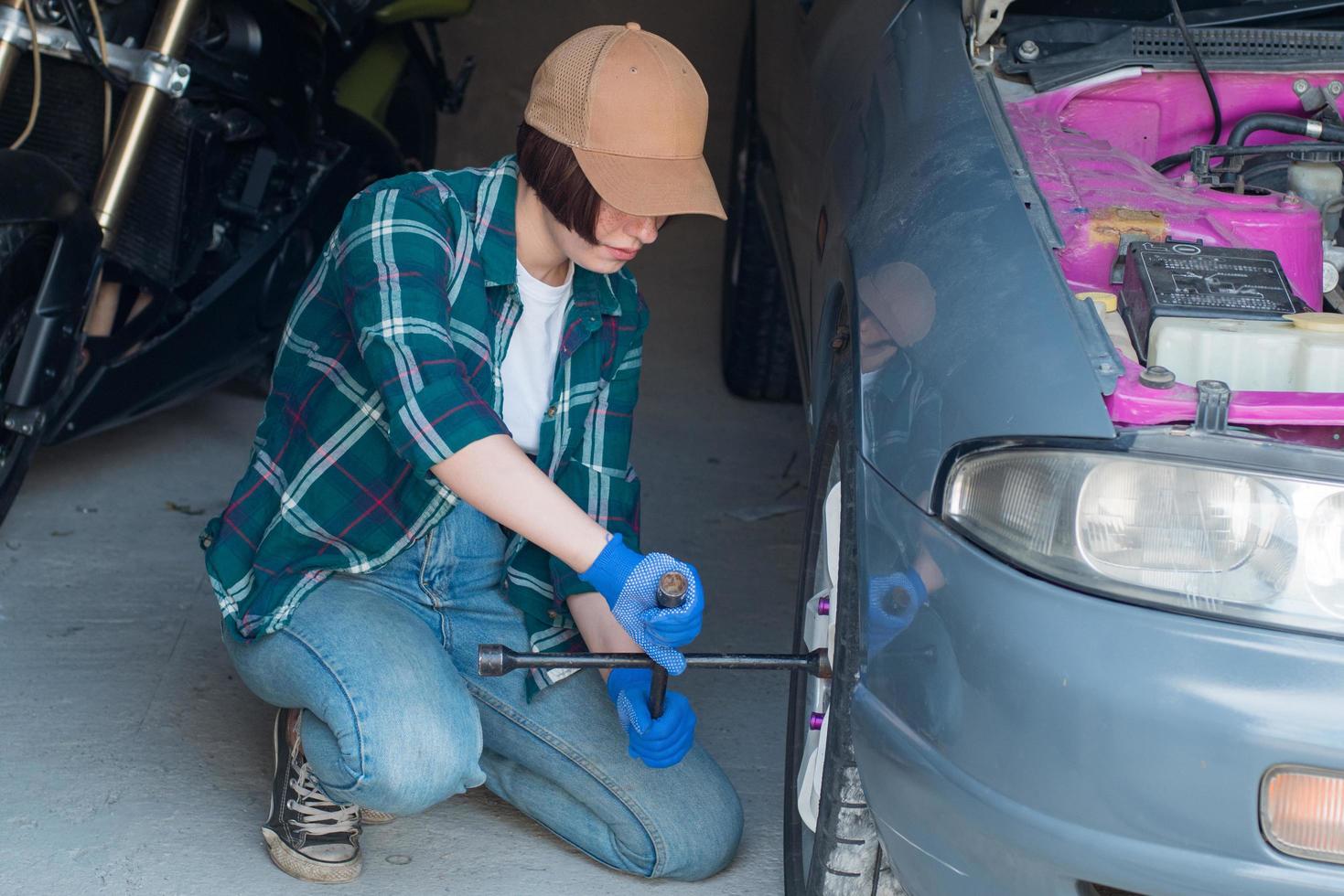 mecânico feminino consertando carro em uma garagem foto