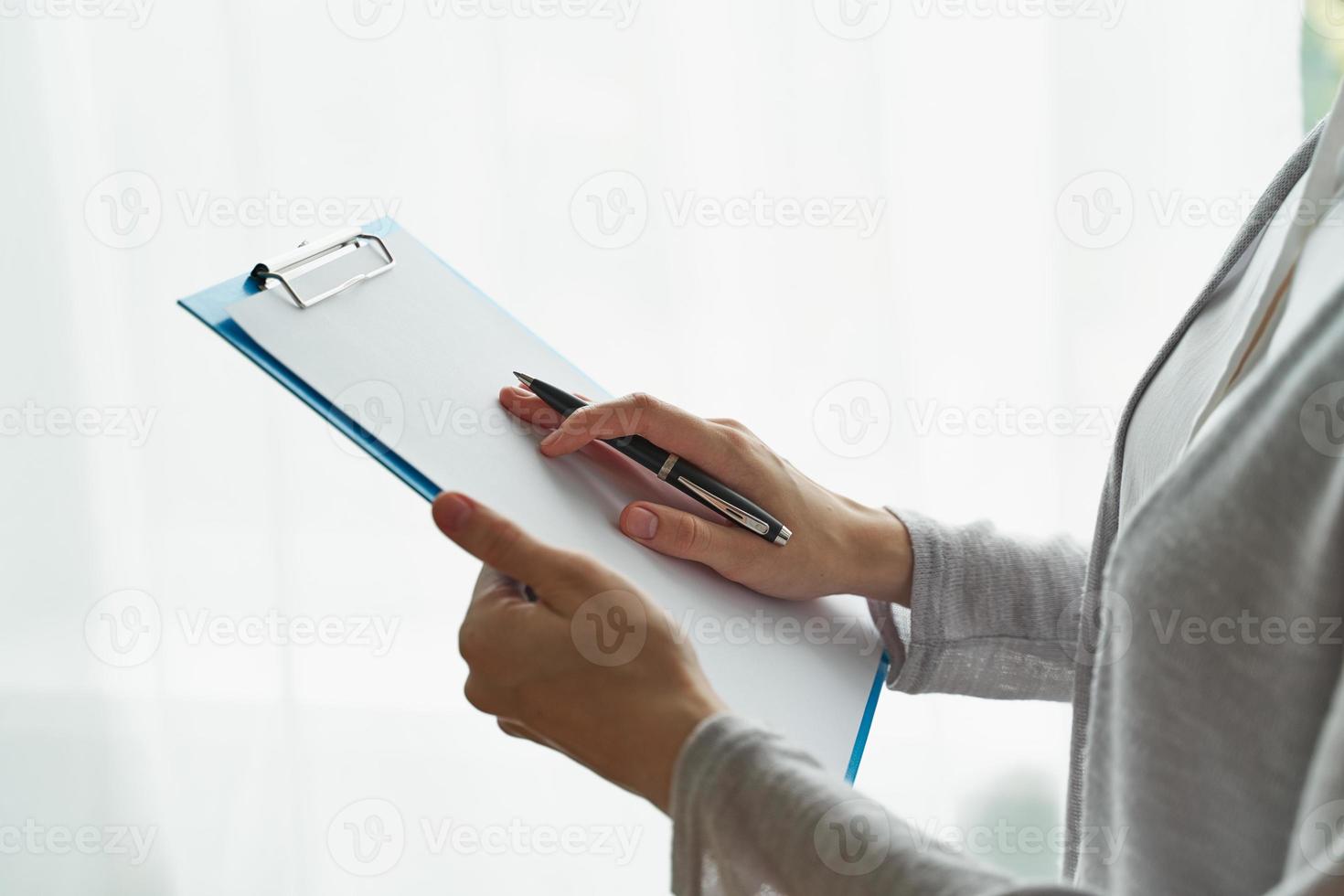 mulher segurando a área de transferência, conceito de trabalho de escritório ou estudando closeup de vista lateral do aluno foto