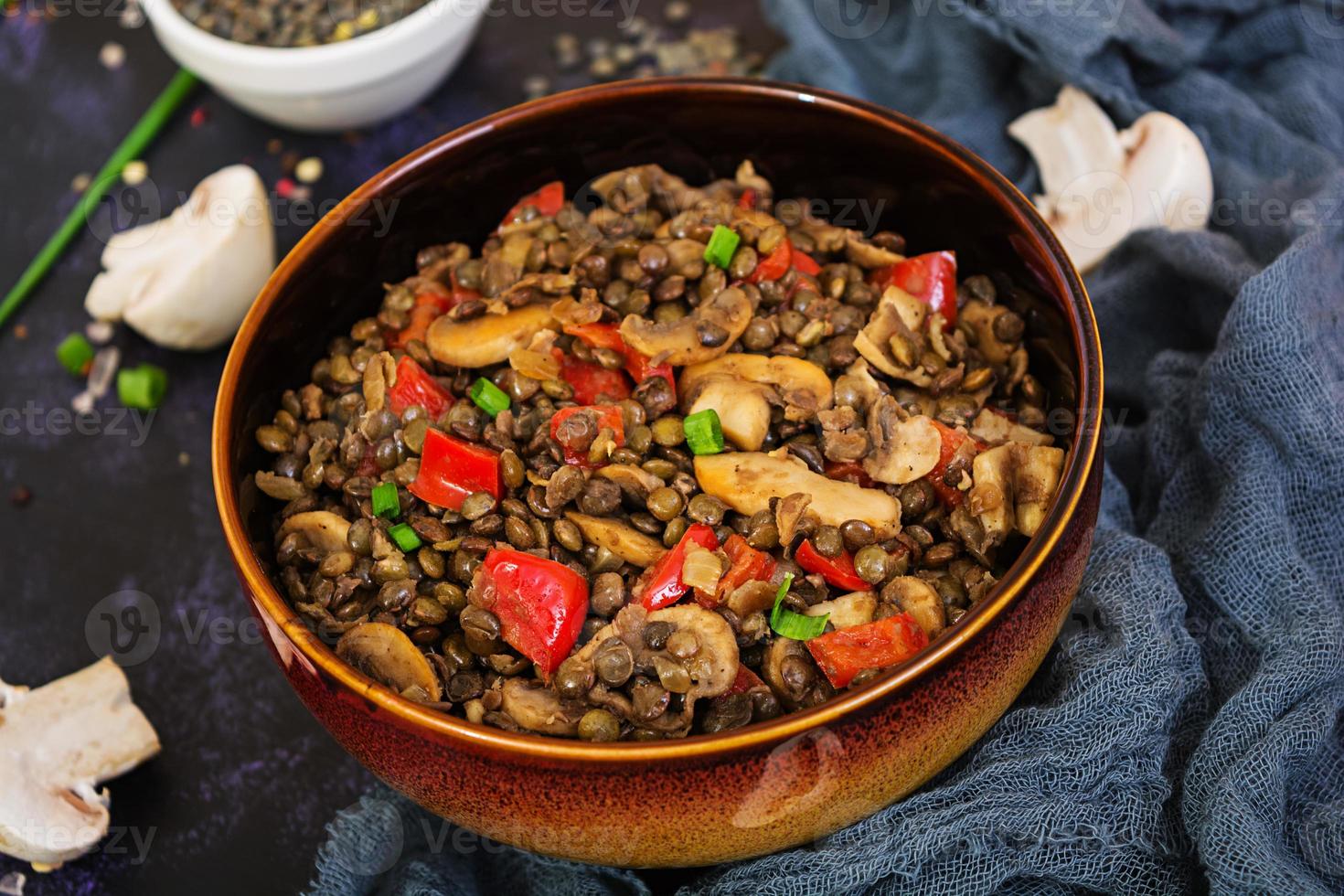 deliciosas lentilhas com pimenta e cogumelos em fundo escuro foto