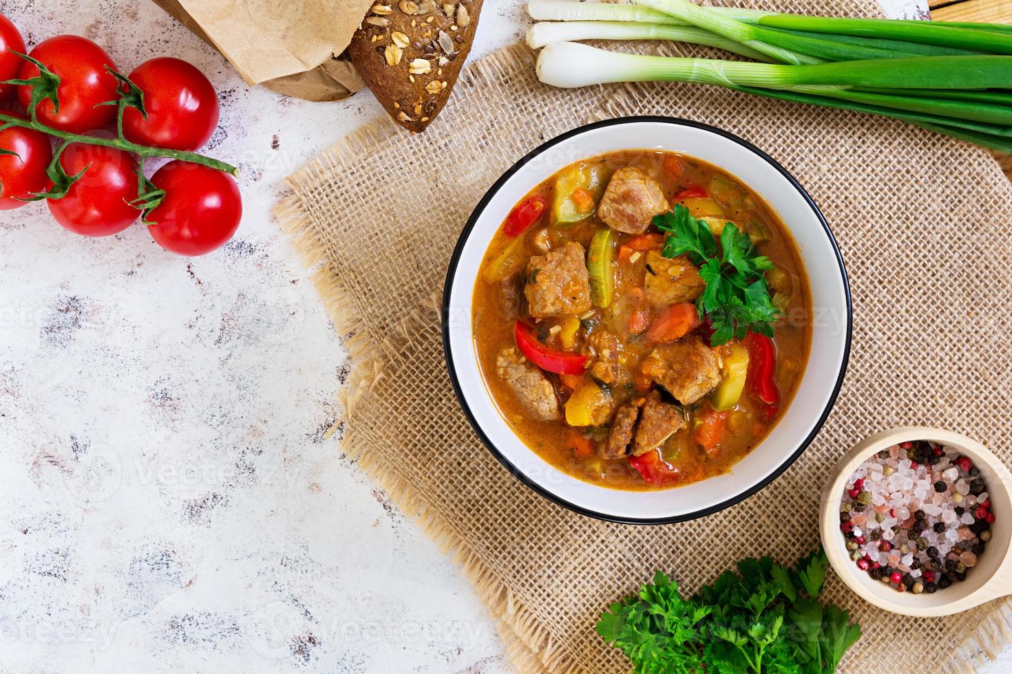 ensopado com carne e legumes em molho de tomate em fundo branco. vista do topo foto