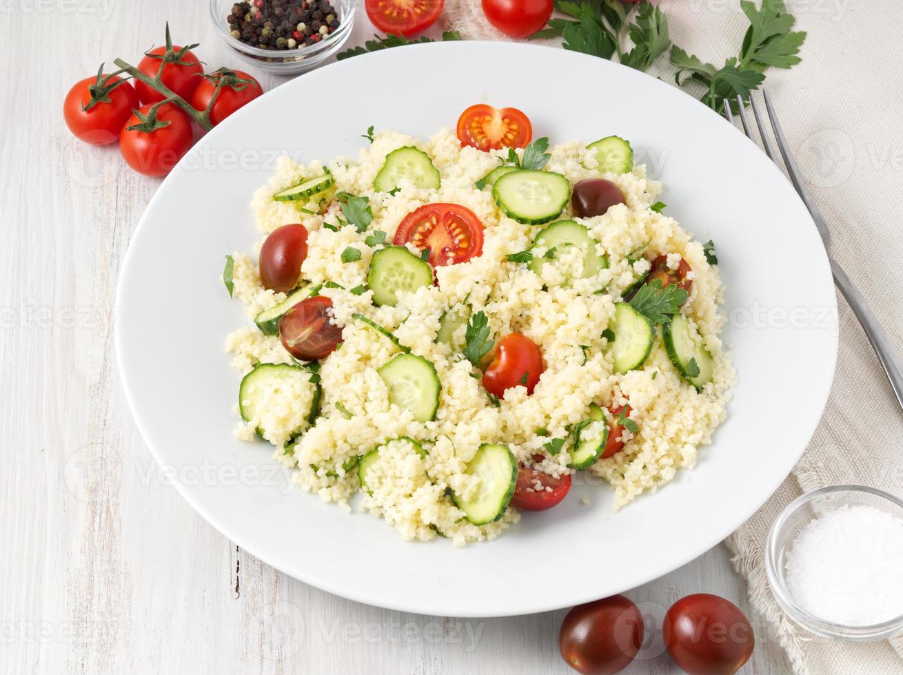 salada de vegetais de dieta fresca com cuscuz, tomate, pepino, salsa, mesa de madeira branca, vista lateral foto