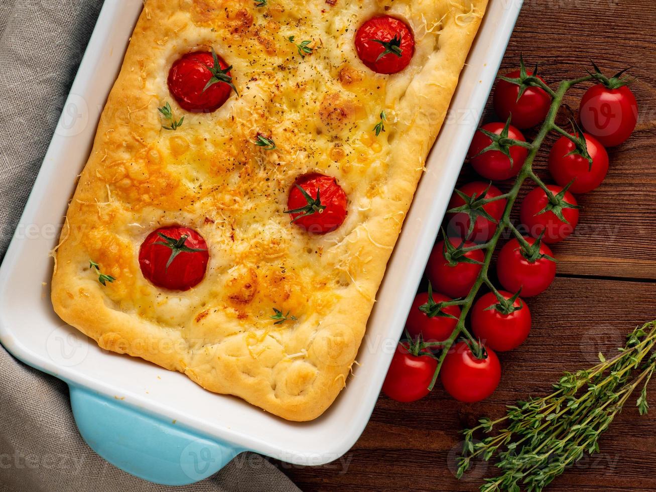 apetitosa focaccia dourada com tomate e especiarias, na mesa rústica de madeira escura foto