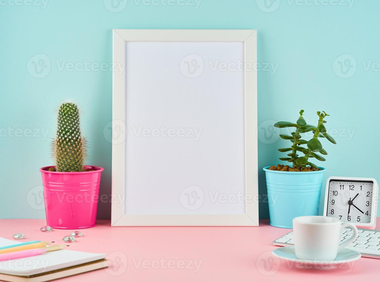 maquete com moldura branca em branco, alarme, bloco de notas, xícara de café ou chá na mesa rosa foto