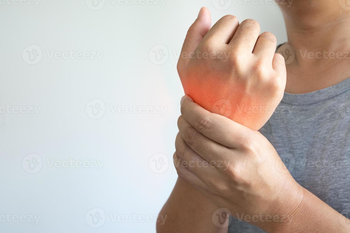 closeup de braços masculinos asiáticos segurando seu pulso doloroso causado trabalhando duro no computador, laptop. síndrome do escritório dor na mão por doença ocupacional. artrite, conceito de doença neurológica. foto