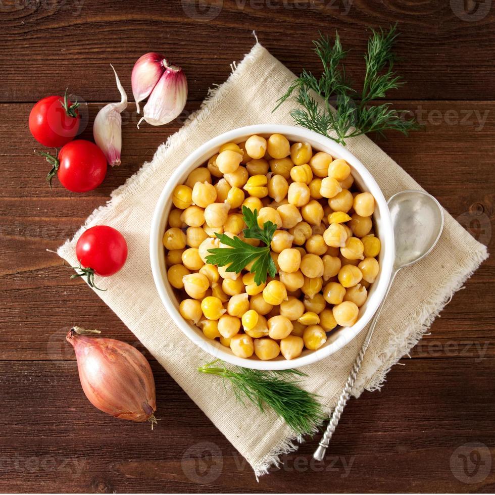 grão de bico cozido na tigela na mesa de madeira escura. saudável, vegetariano foto