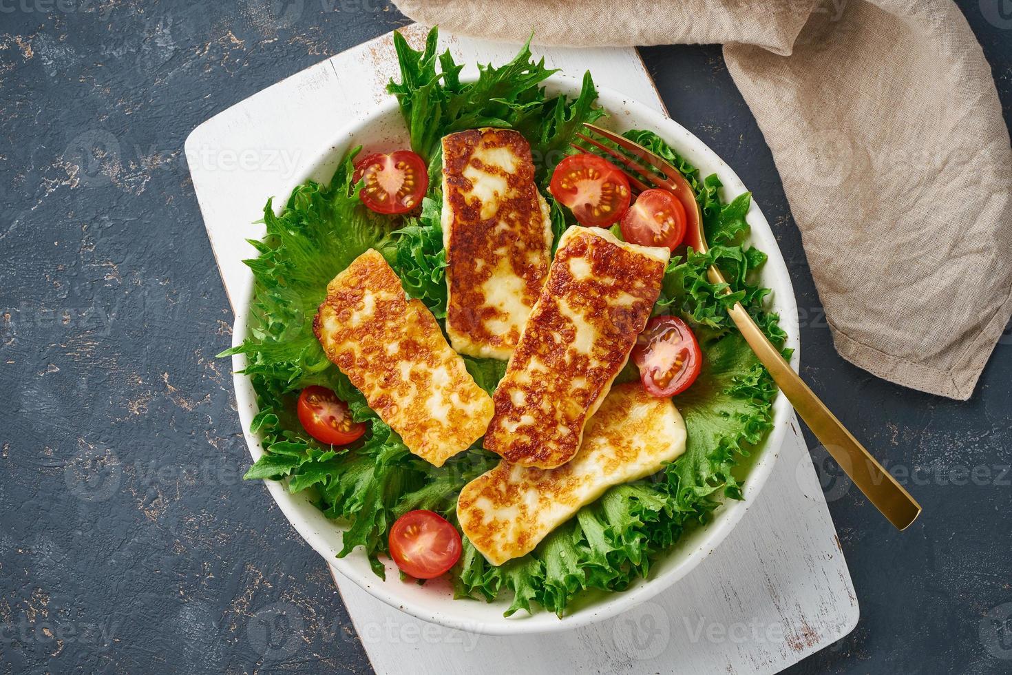 salada vegana com halloumi frito e tomate, fundo escuro, vista superior foto