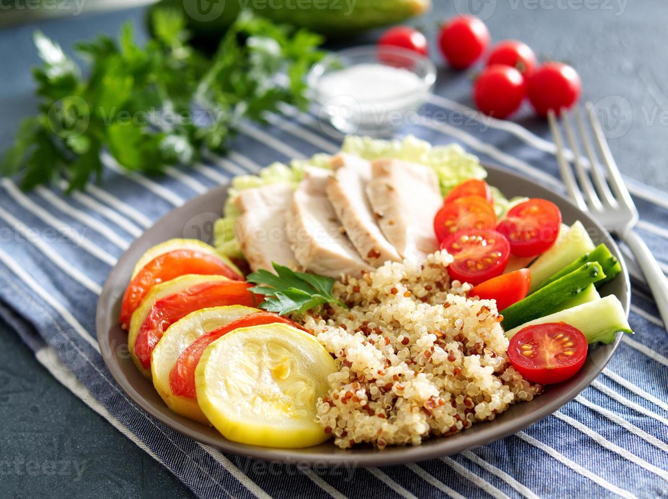 almoço de tigela de buda vegetal saudável com peru, legumes e quinoa em fundo azul. vista lateral. foto