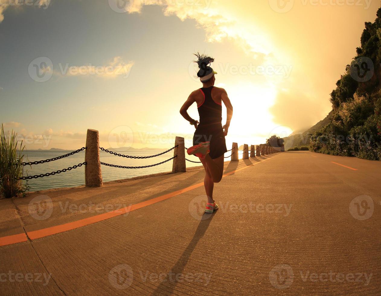 mulher jovem fitness correndo na trilha à beira-mar do nascer do sol foto