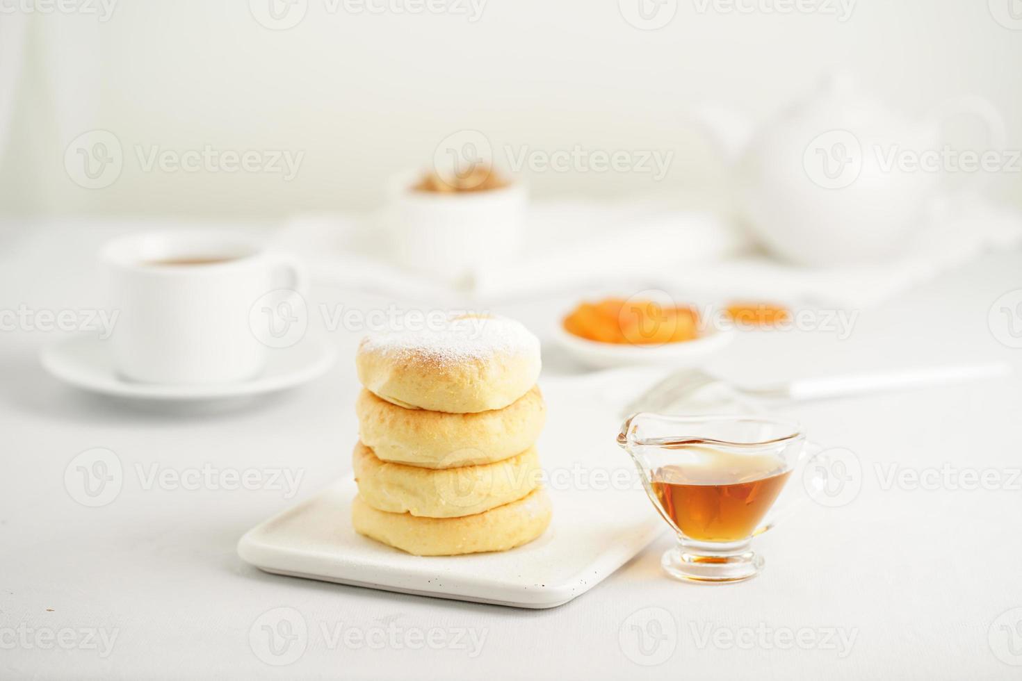 bolos de queijo frito, panquecas de queijo doce na chapa branca sobre fundo branco. chá de casa foto