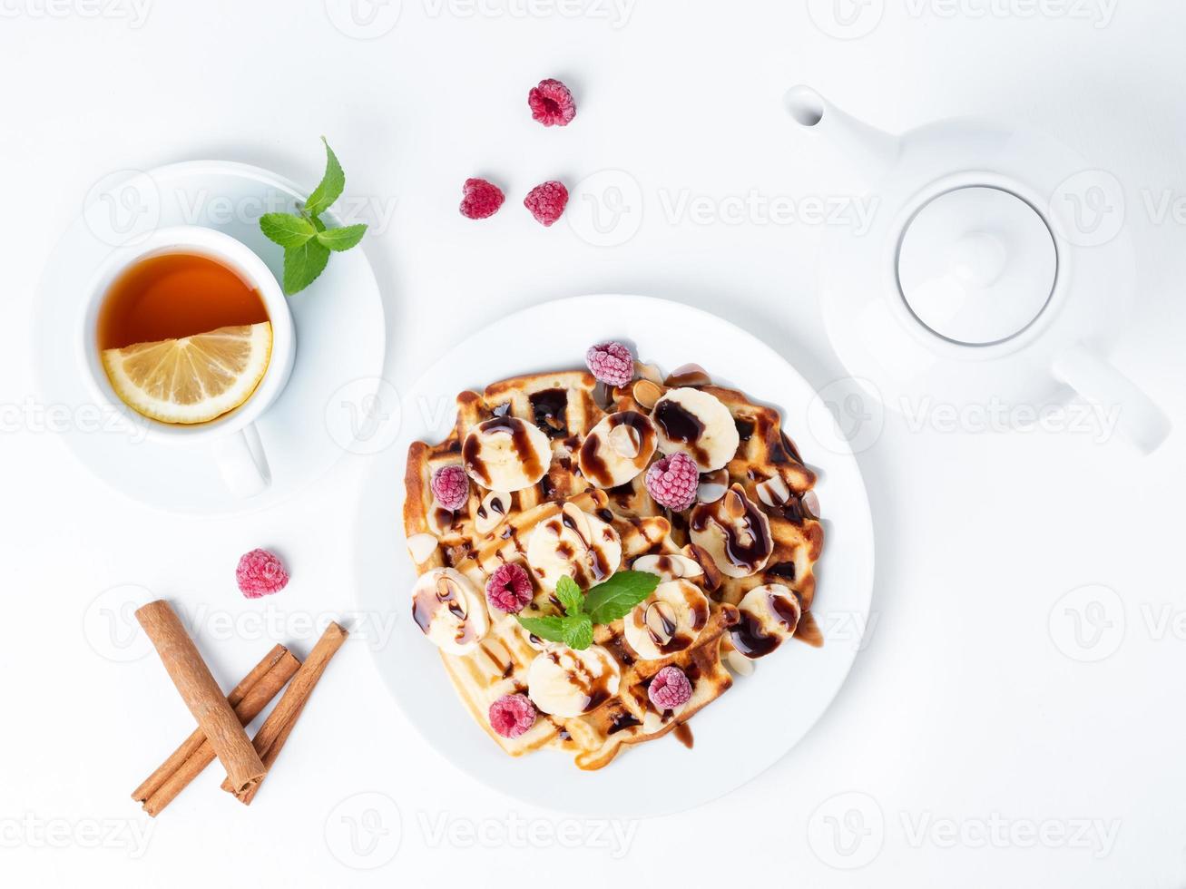 waffles de coalhada belga com framboesas, banana, calda de chocolate. café da manhã com chá no fundo branco, vista superior foto