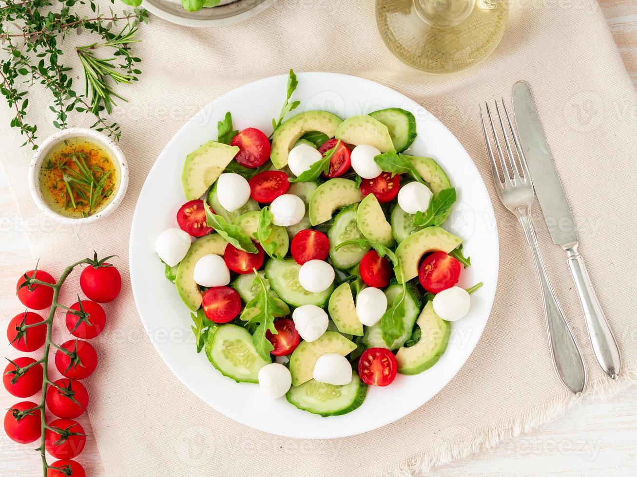 salada fresca com tomates pepinos rúcula mussarela e abacate. óleo com especiarias, vista superior foto