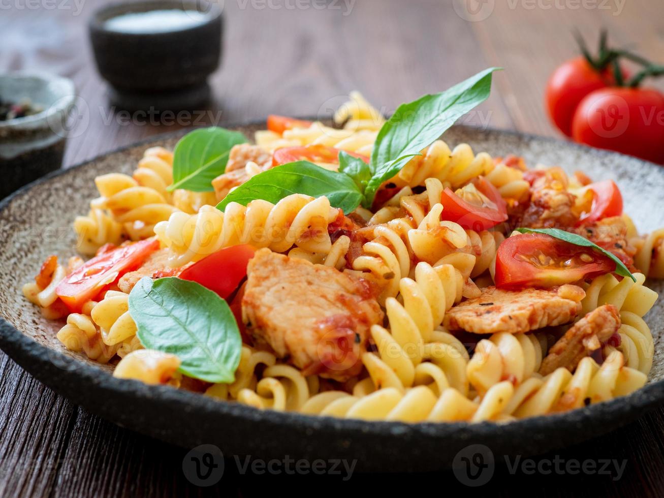 massa fusilli com molho de tomate, filé de frango com folhas de manjericão foto