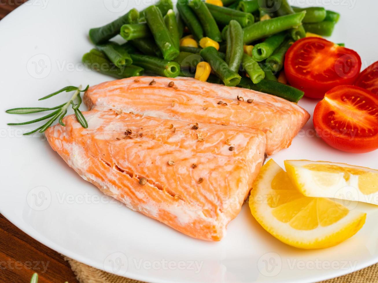 peixe salmão cozido no vapor com legumes. comida de dieta saudável, pano de fundo de madeira escura foto