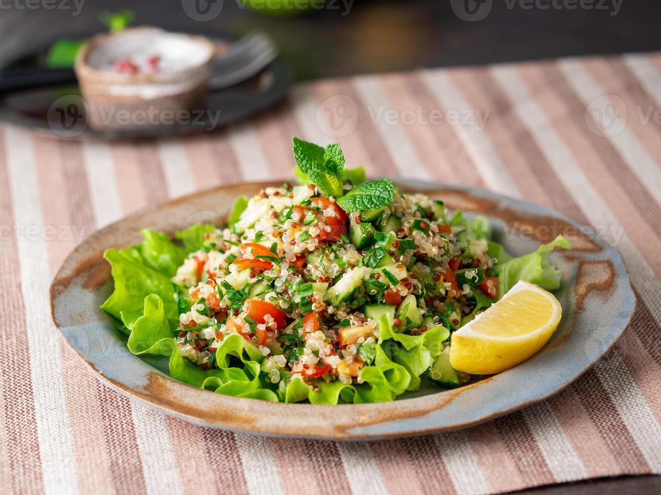 salada de tabule com quinoa. comida oriental com mix de legumes, dieta vegana. vista lateral, guardanapo de linho, prato antigo foto