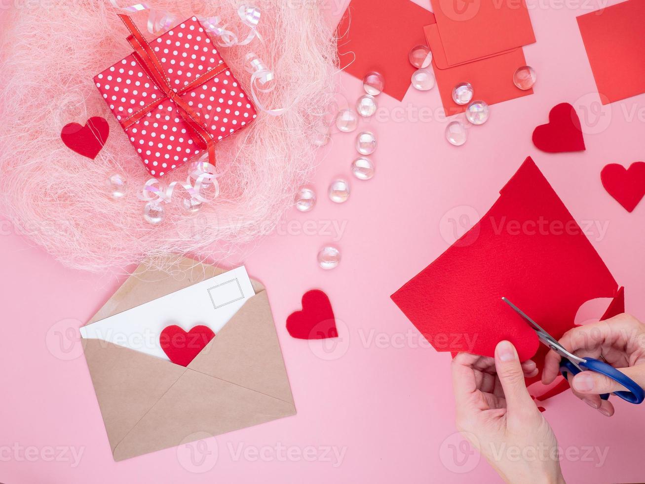 mulher corta corações de feltro vermelho, artesanato caseiro para o dia dos namorados, criatividade feita à mão, vista superior foto