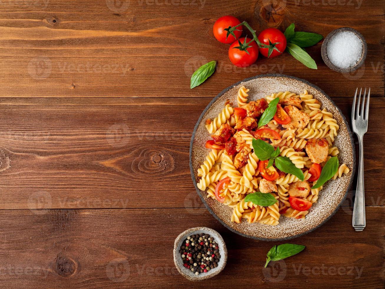 massa fusilli com molho de tomate, filé de frango com folhas de manjericão foto