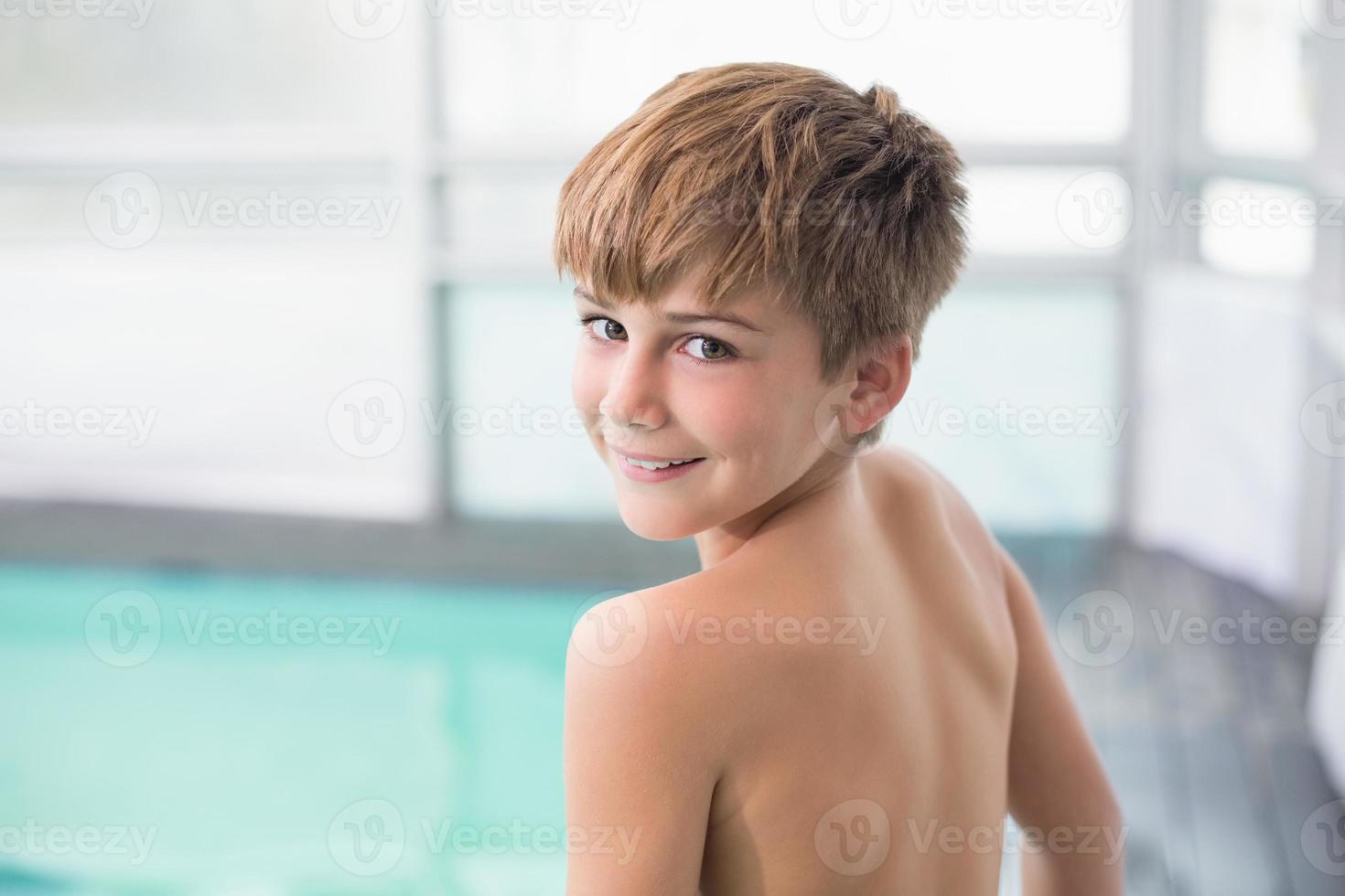 menino bonitinho em pé à beira da piscina foto