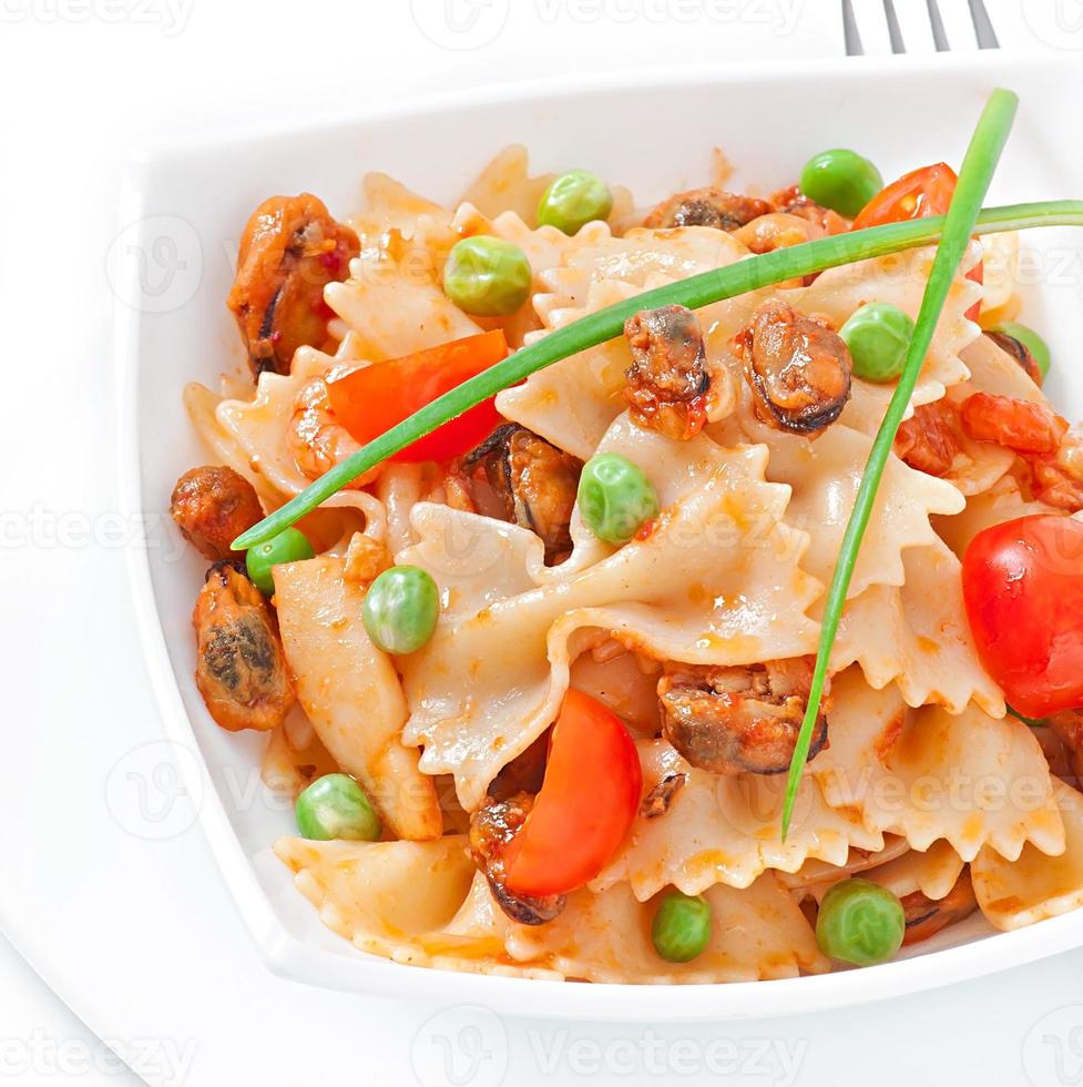 massa farfalle com frutos do mar, tomate cereja e ervilhas verdes foto