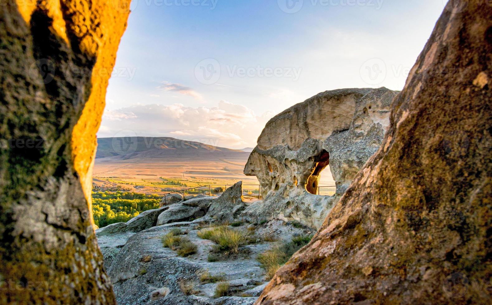 vista panorâmica de grande angular para estruturas da cidade da caverna uplistsikhe com fundo de paisagem natural do pôr do sol foto