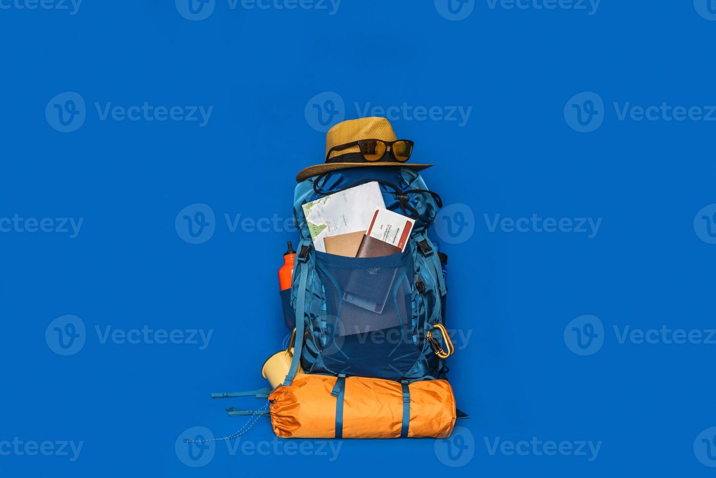 turismo planejando férias com a ajuda do mapa-múndi com outros acessórios de viagem ao redor. bagagem de conceito com acessório para férias de viajantes sobre fundo de cor azul. mochila de viagem foto