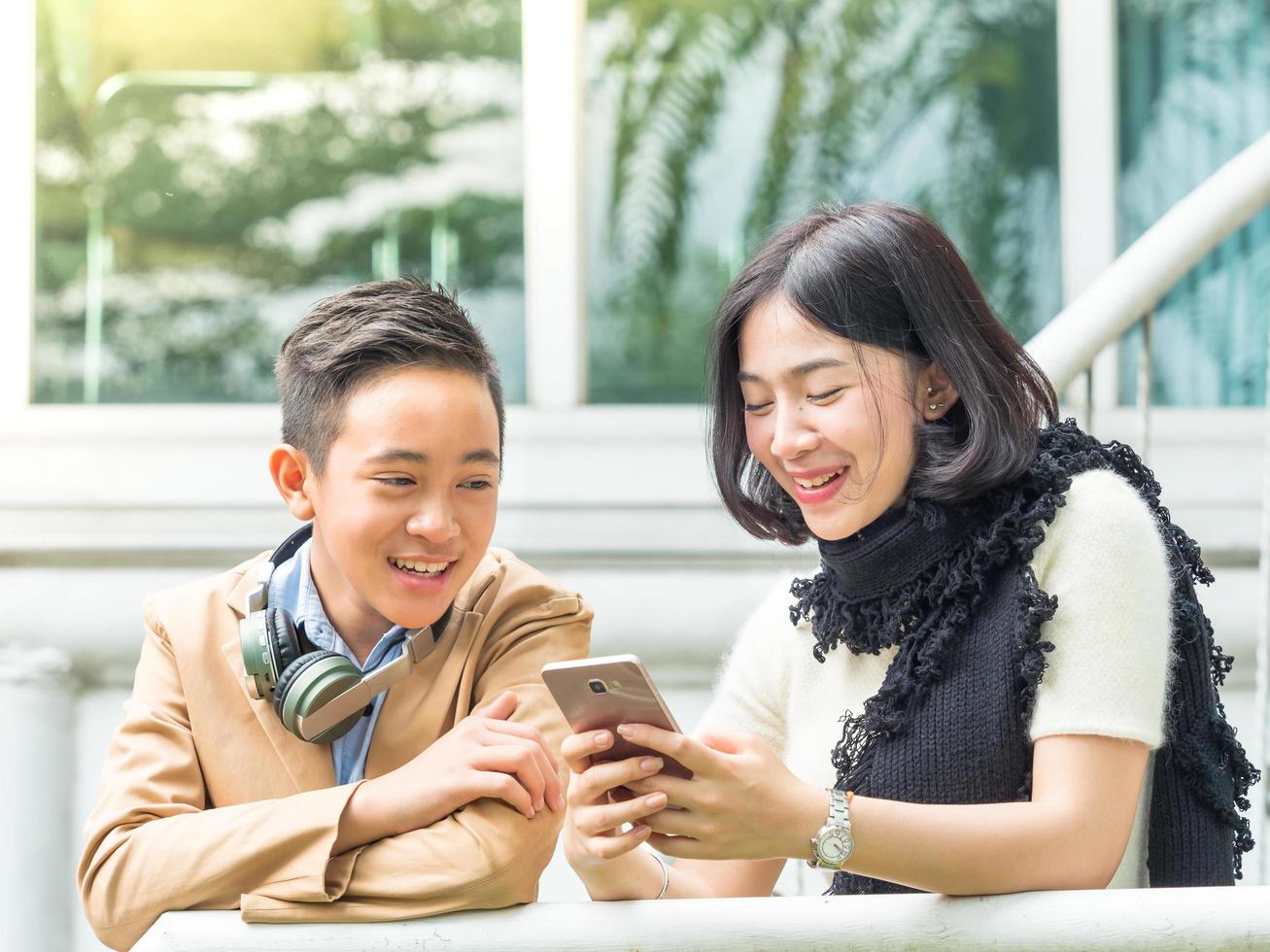 Dois adolescentes, menino e menina, jogam jogo para celular em