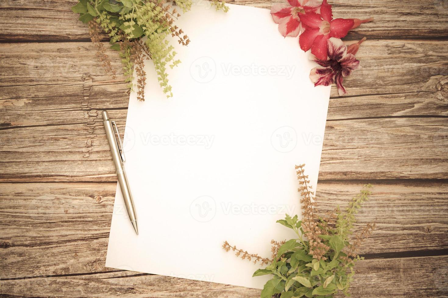 espaço conceitual para o texto, que consiste em papel em branco, azaléia, flores de manjericão e canetas em um fundo de madeira. modelo em branco para o seu text.top view.flat lay foto