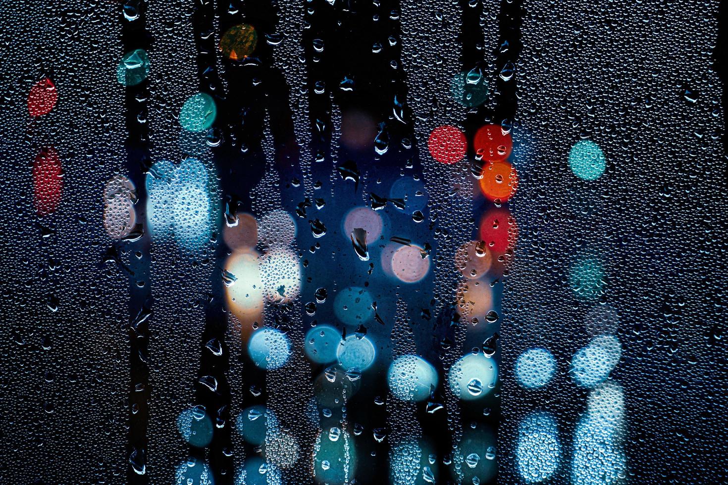 gotas de chuva na janela e luzes da rua à noite foto