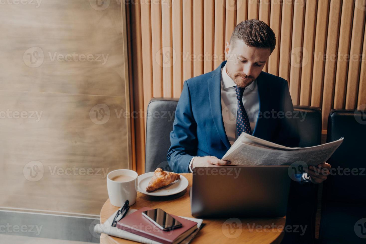 jovem empresário em smoking formal lendo jornal no café foto