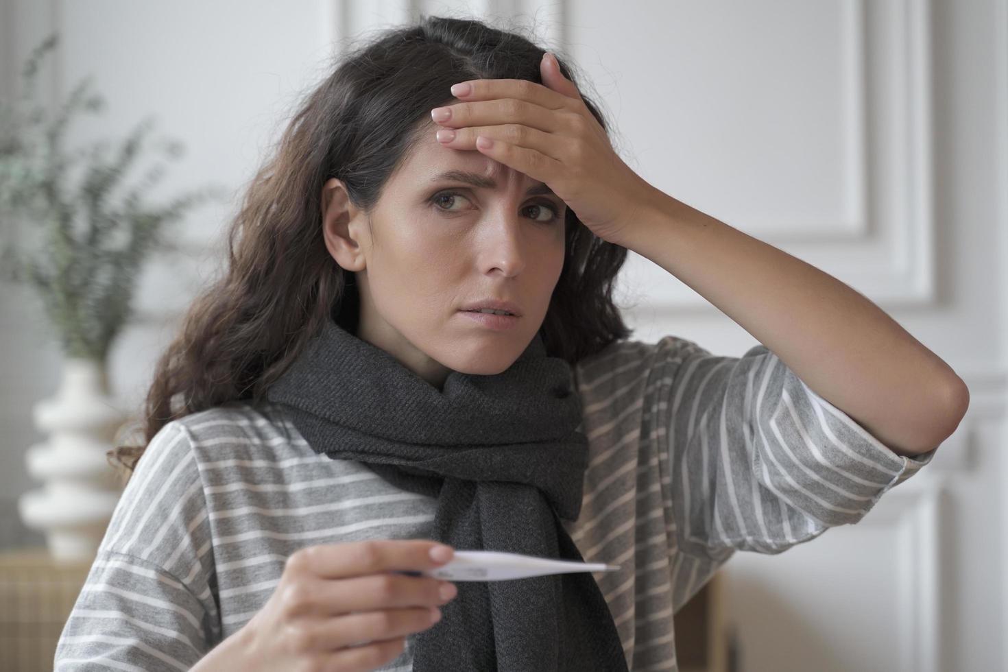 triste e doente jovem italiana usando cachecol de malha no pescoço, sofrendo de gripe e resfriado em casa foto