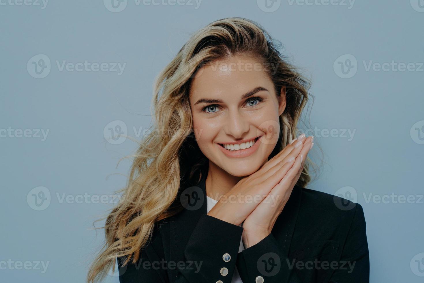 sorrindo alegre loira adolescente descansando a cabeça nas mãos e sorrindo para a câmera foto