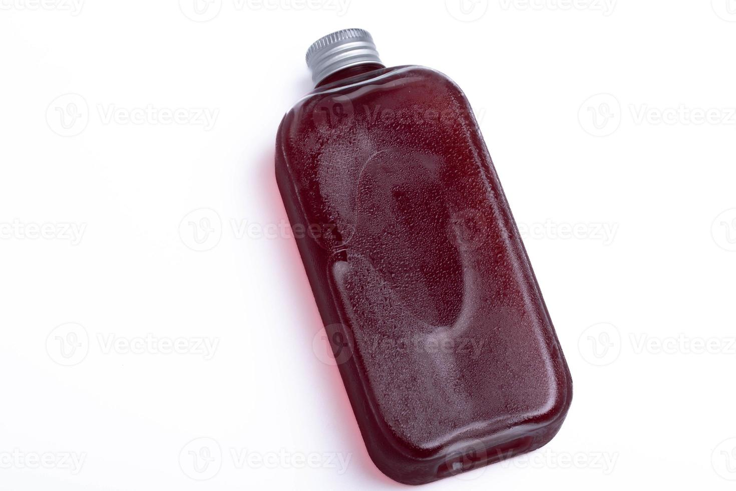suco de uva em uma garrafa transparente em um fundo branco foto