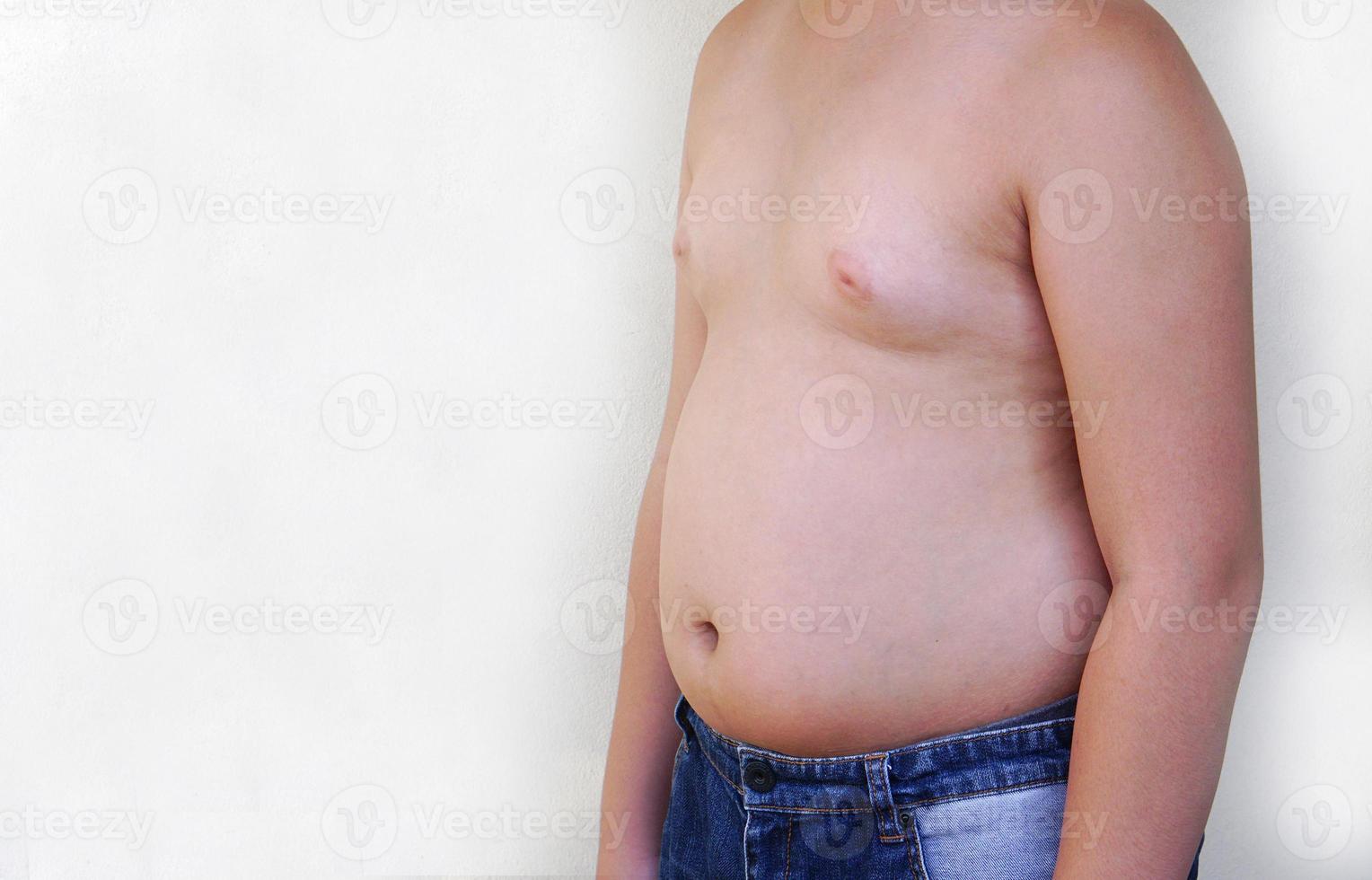 um menino gordo usa jeans em pé sobre um fundo branco. foto