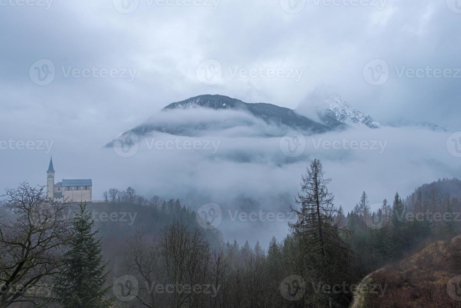 pequena igreja no meio do nevoeiro da montanha foto