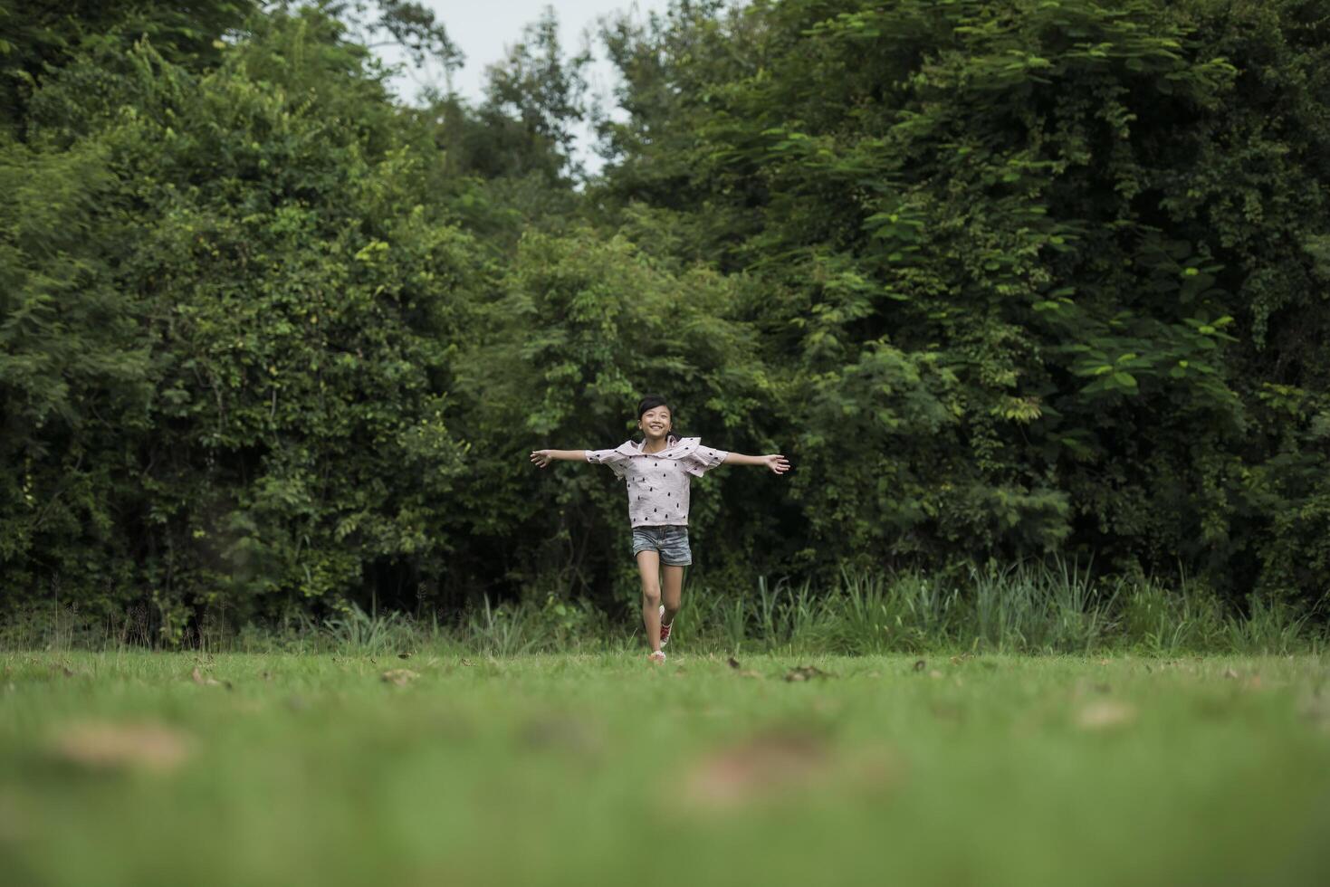 menina feliz e fofa correndo na grama do parque foto