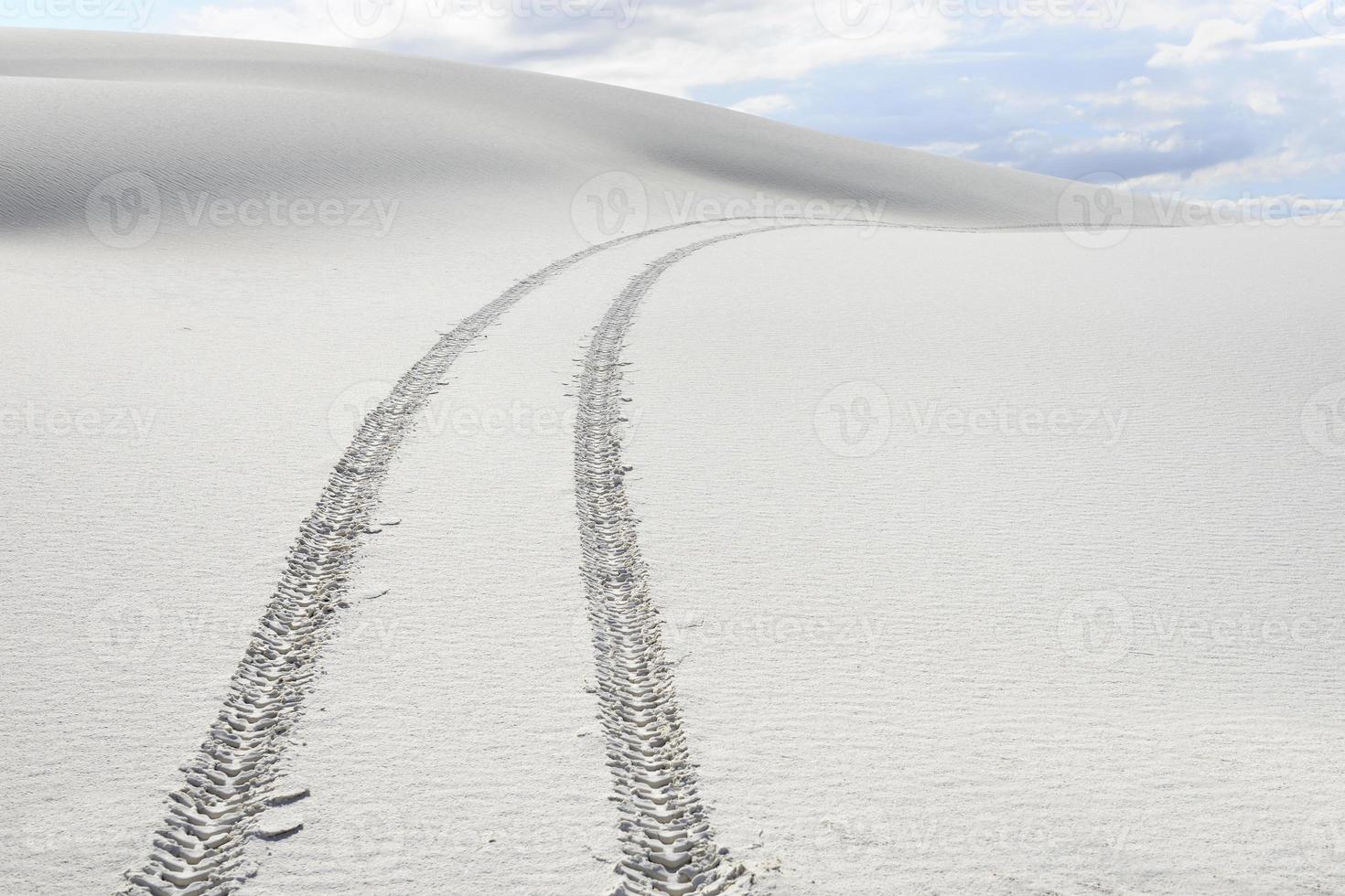 trilhas de pneu através de dunas de areia branca foto
