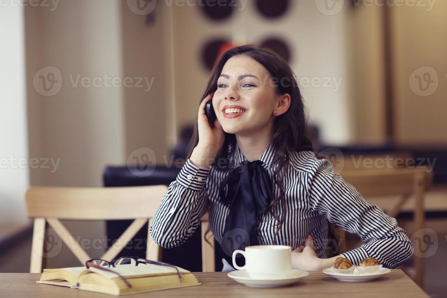 menina falando ao telefone em um café foto