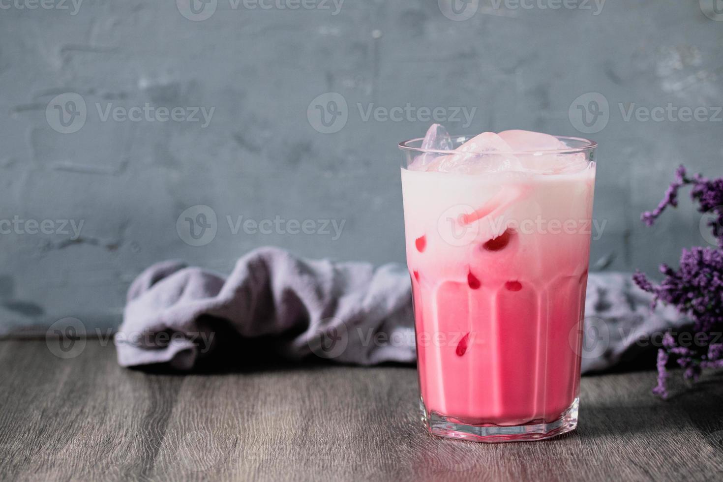 bebida gelada de leite rosa frio em vidro transparente em fundo cinza. leite tailandês foto