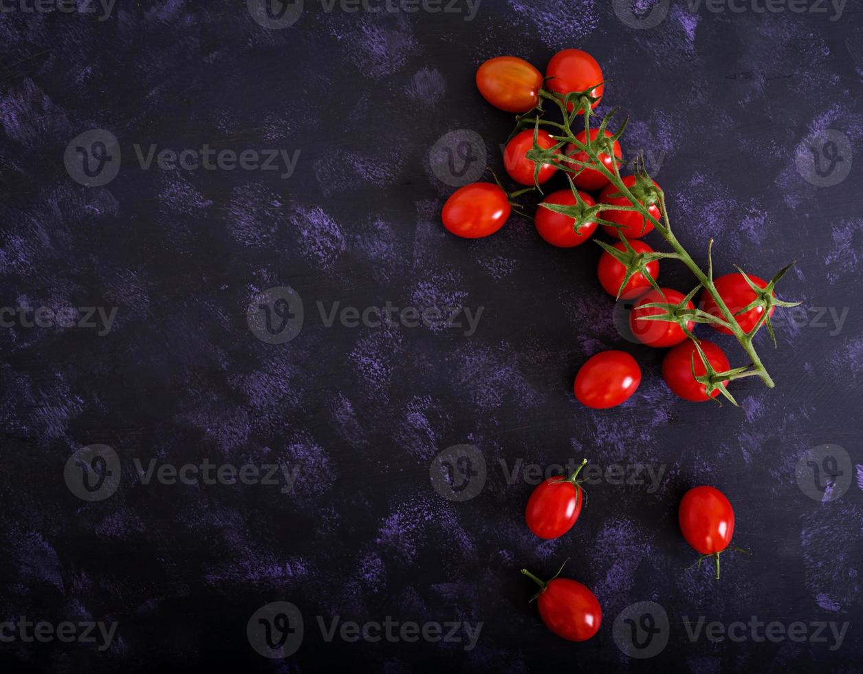 tomates cereja maduros frescos em um fundo escuro. vista do topo foto