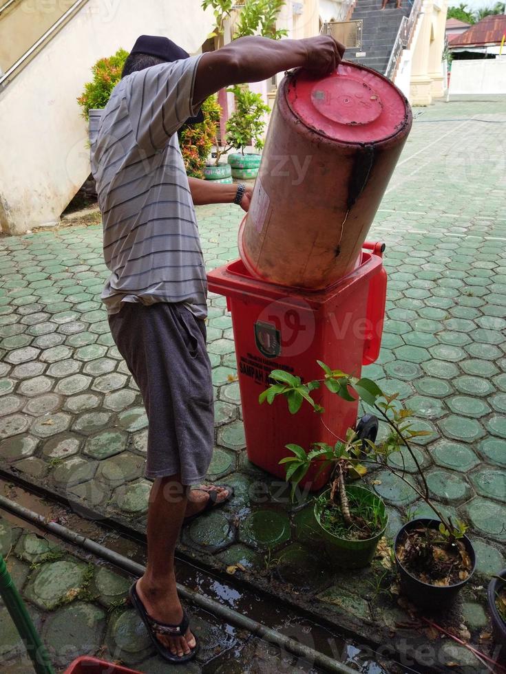 um lixeiro está despejando lixo em uma lata de lixo laranja foto