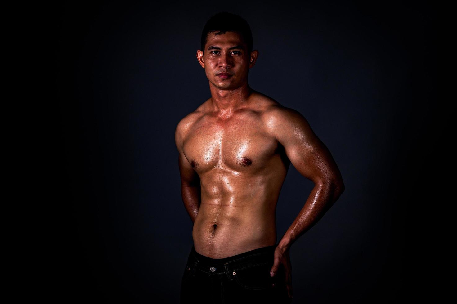 um homem asiático forte levantou os braços para mostrar seus músculos fortes e bonitos do exercício foto