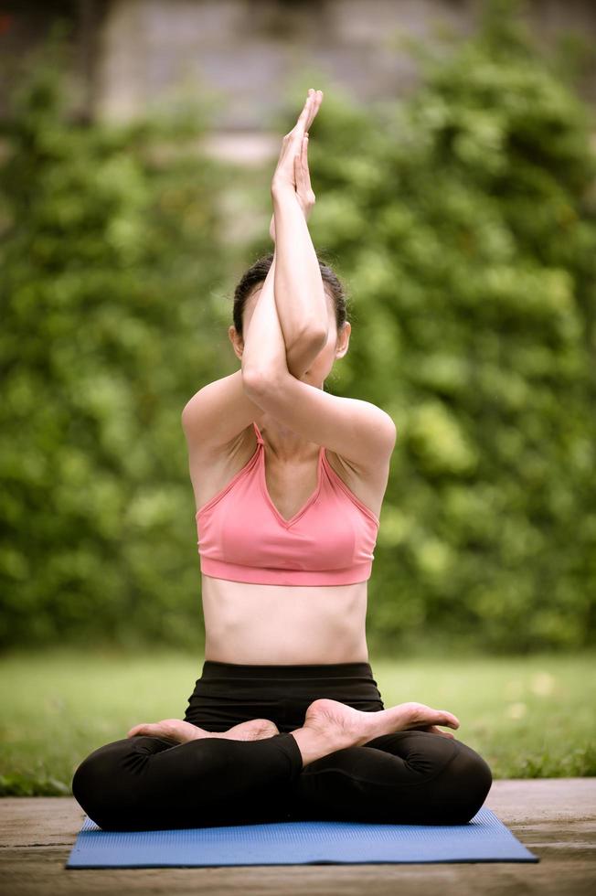 mulheres asiáticas meditando e alongando relaxam seus músculos fazendo ioga no jardim foto