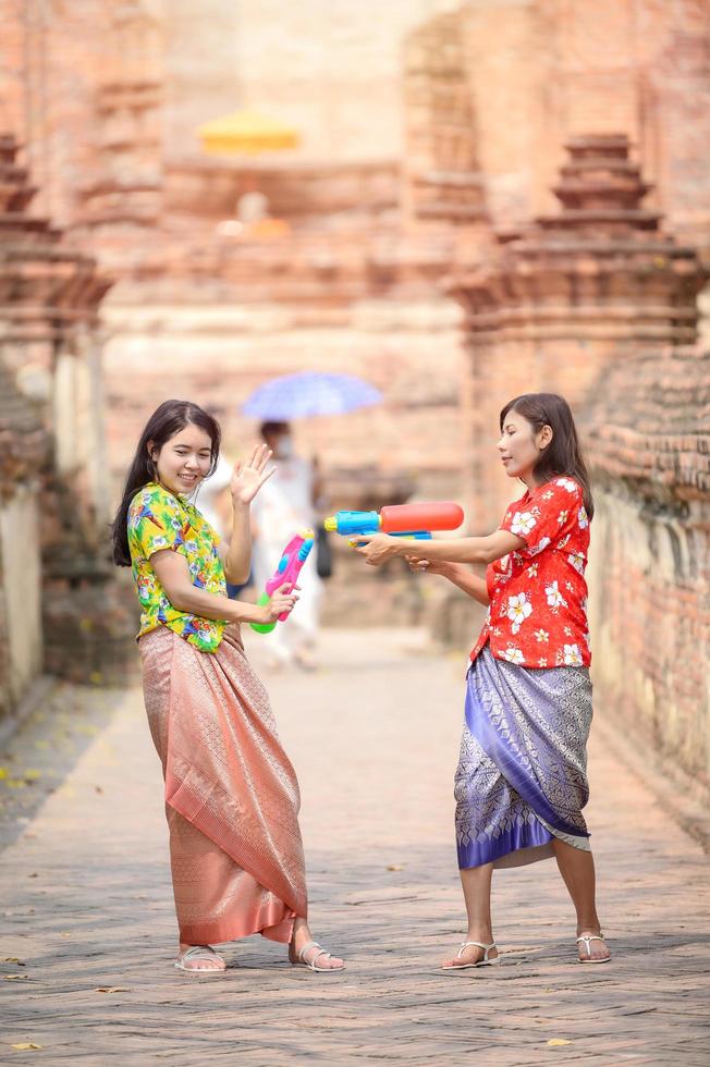 belas mulheres asiáticas seguram pistolas de água de plástico em um templo antigo durante songkran, o festival de água mais bonito e divertido da tailândia foto