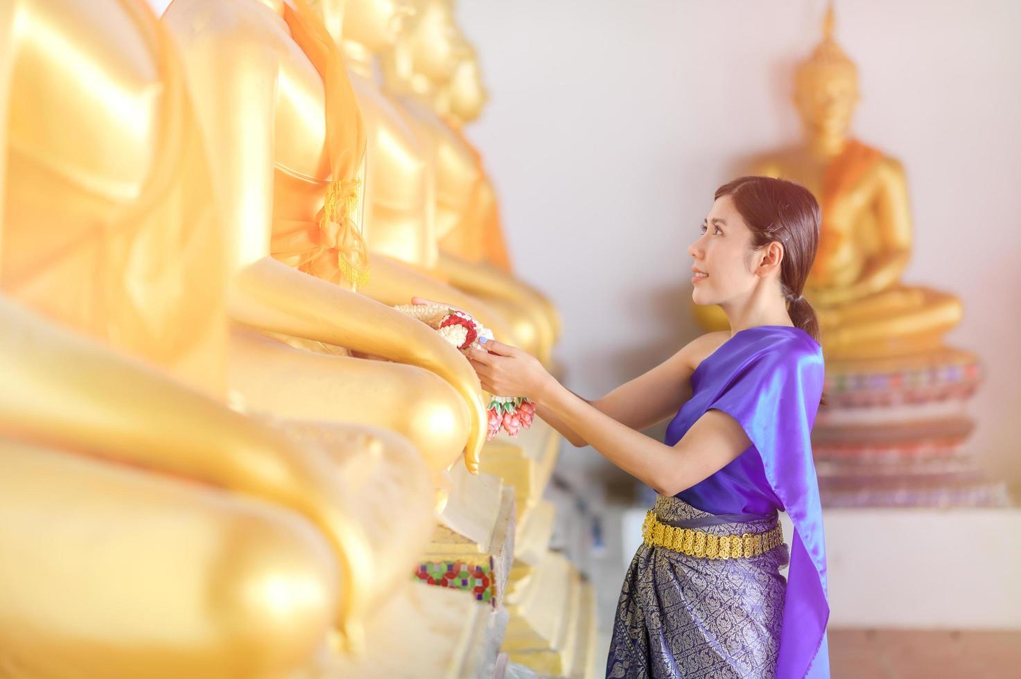 mulher tailandesa atraente em um vestido tailandês antigo segura uma guirlanda de flores frescas em homenagem ao buda para fazer um desejo no tradicional festival songkran na tailândia foto