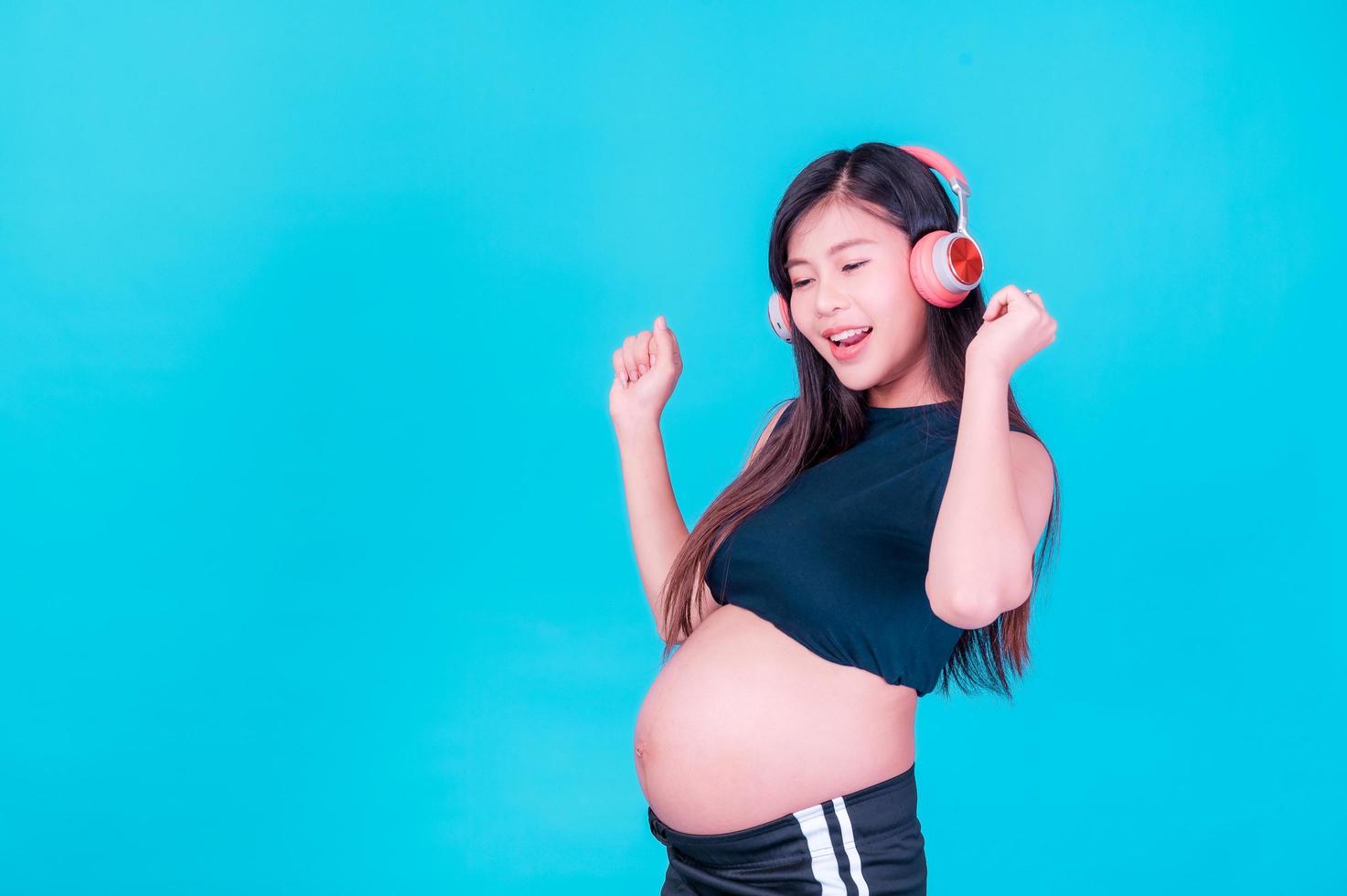 mulher grávida bonita asiática fica relaxada e gosta de ouvir música em fones de ouvido conectados à internet foto