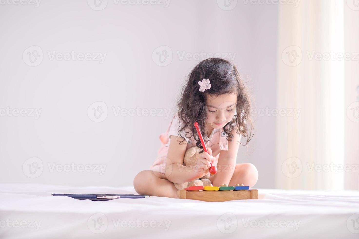 uma linda jovem asiática estava alegremente tocando um instrumento de brinquedo de madeira no quarto foto