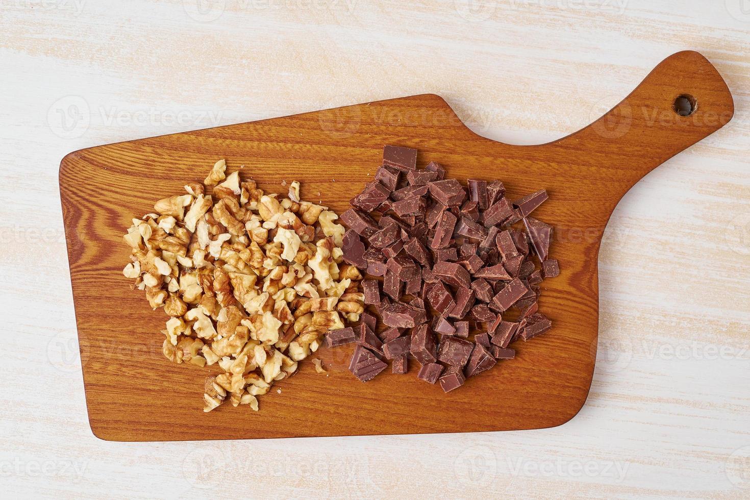 nozes picadas e chocolate na placa de madeira. receita passo a passo de pão de banana. foto