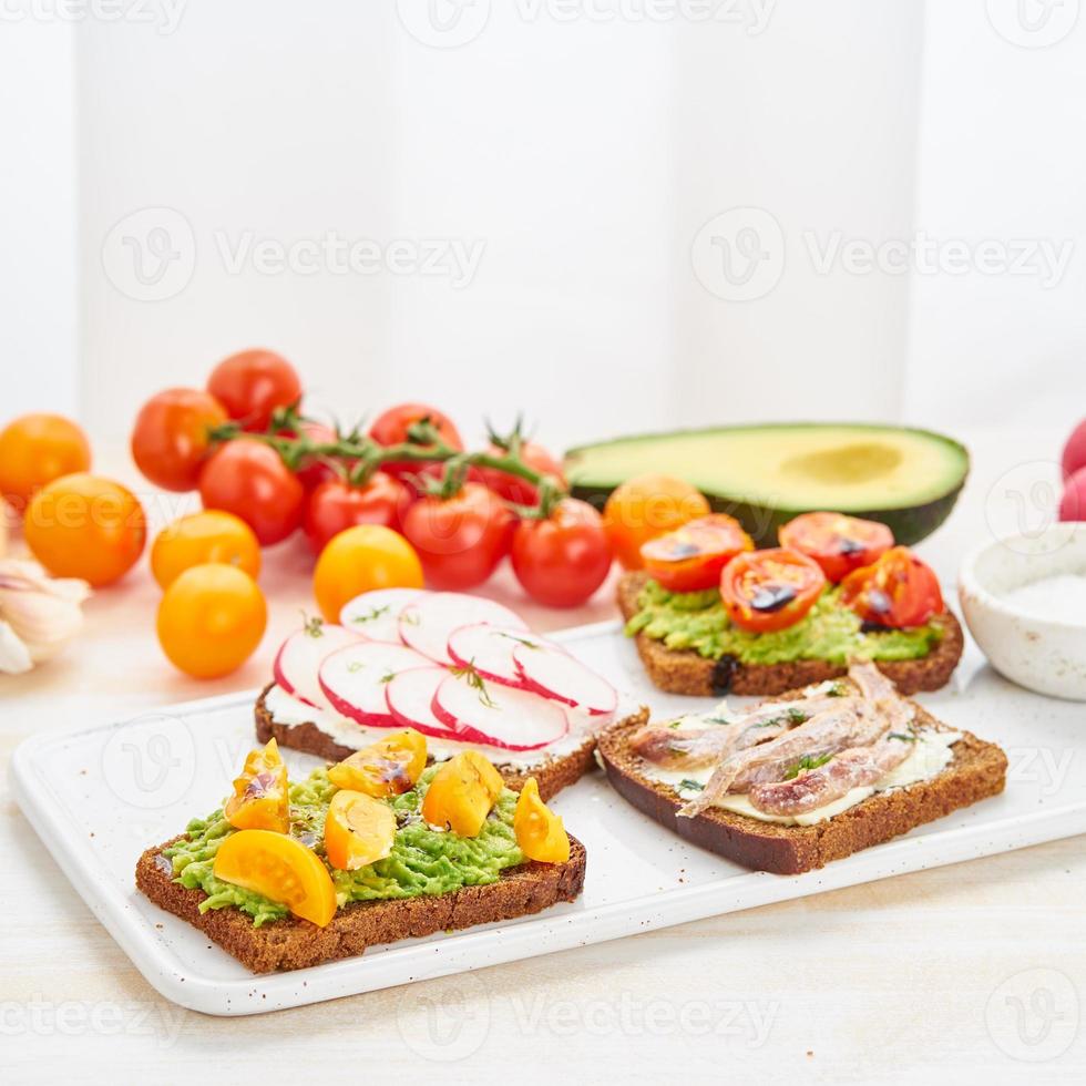 conjunto de smorrebrods com peixe, anchovas, abacate, tomate, rabanete. foto