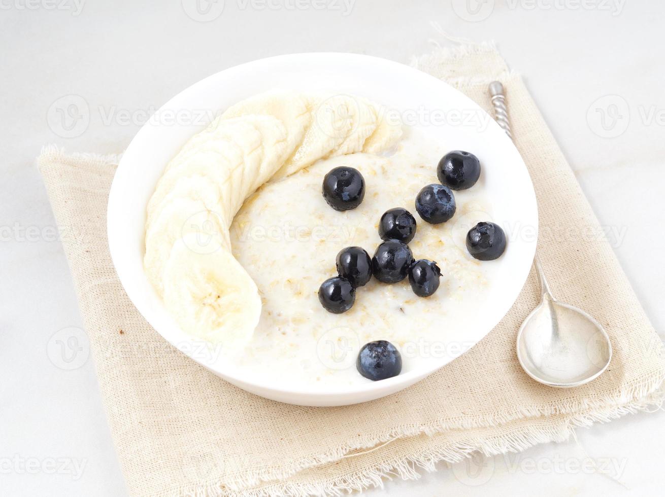 tigela grande de aveia saborosa e saudável com frutas e bagas no café da manhã, refeição matinal. vista lateral, mesa de mármore branco foto