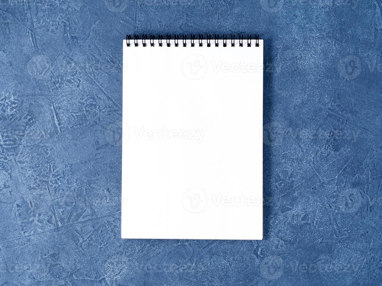 o bloco de notas aberto com página branca limpa na mesa de pedra azul escura envelhecida, vista superior foto